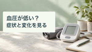 血圧計と腕帯、白紙のノート。血圧が低い？／症状と変化を見る。記事の趣旨を表した生成イメージ